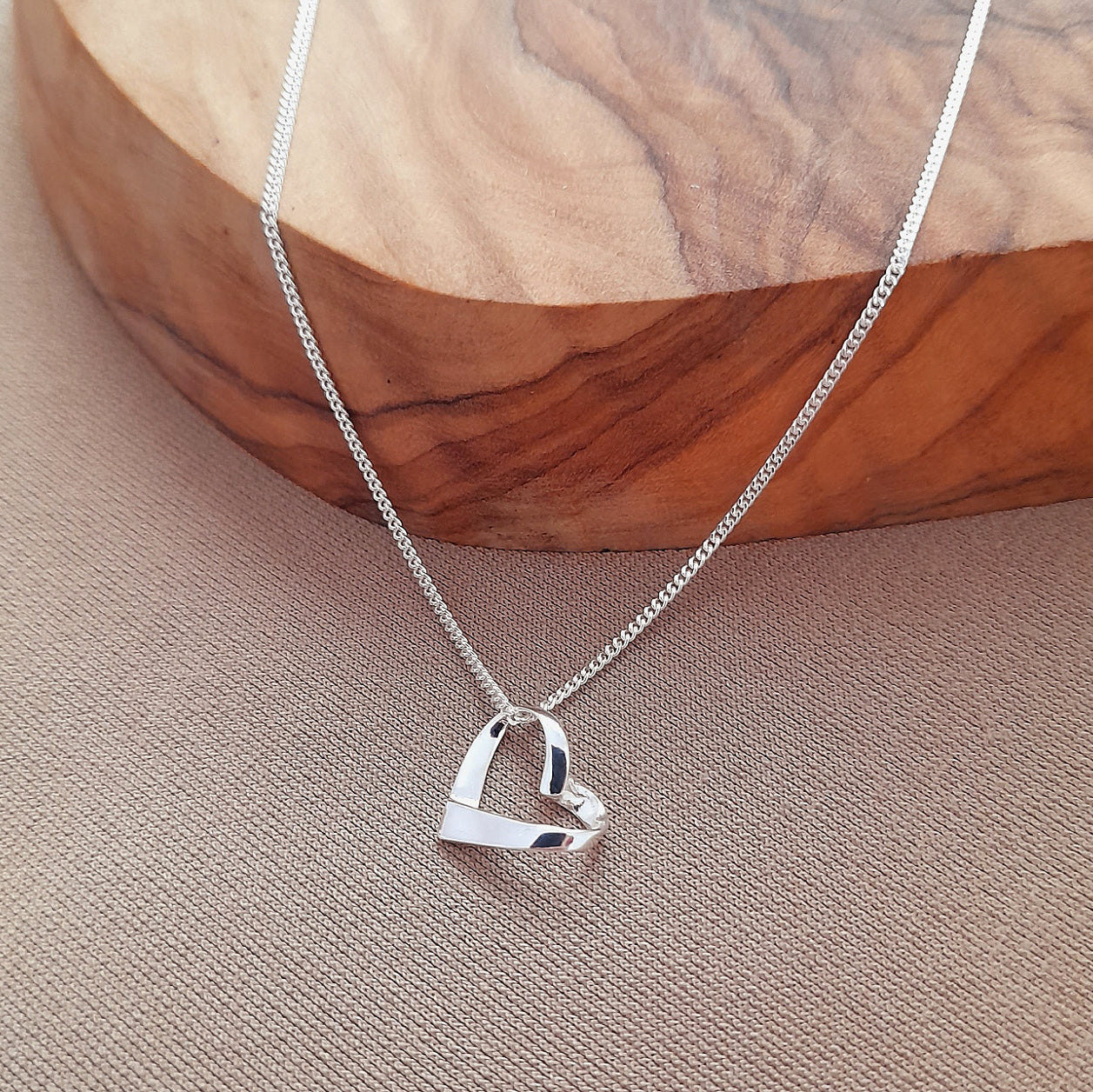 Silver heart-shaped pendant necklace on a wooden surface