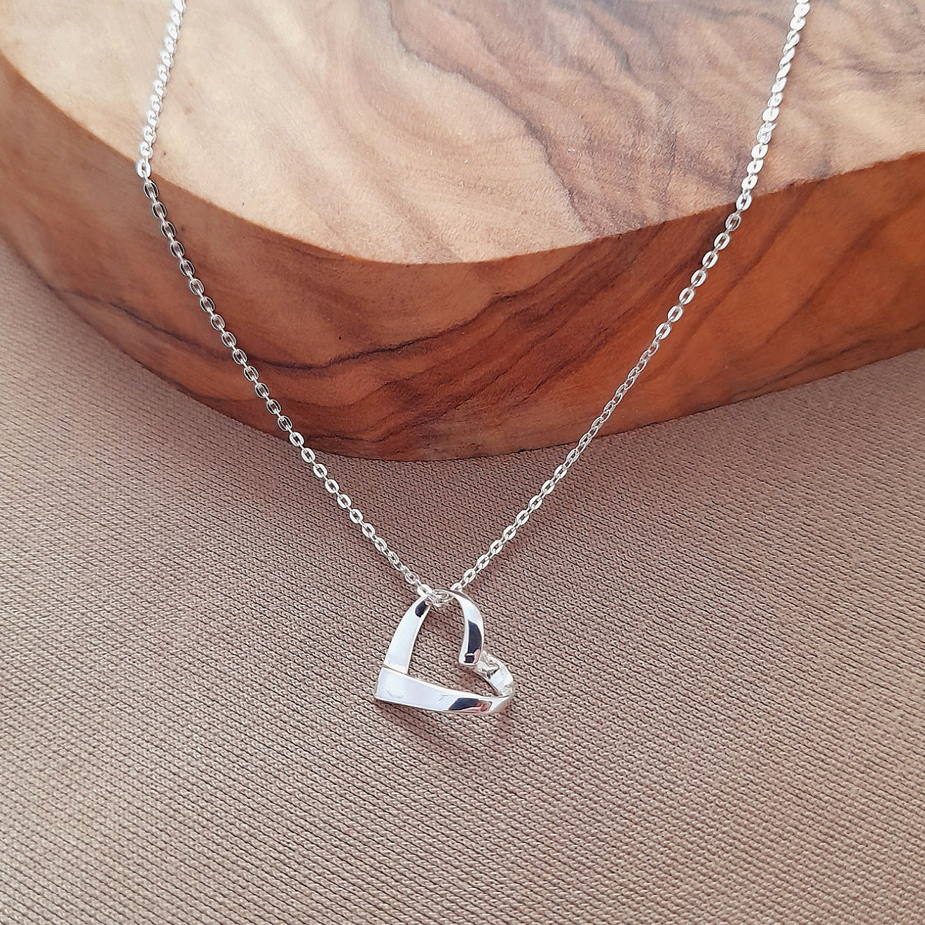 Silver heart-shaped pendant necklace on a wooden surface